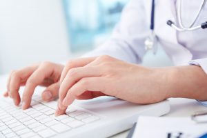 Close-up of hands of a nurse typing on laptop